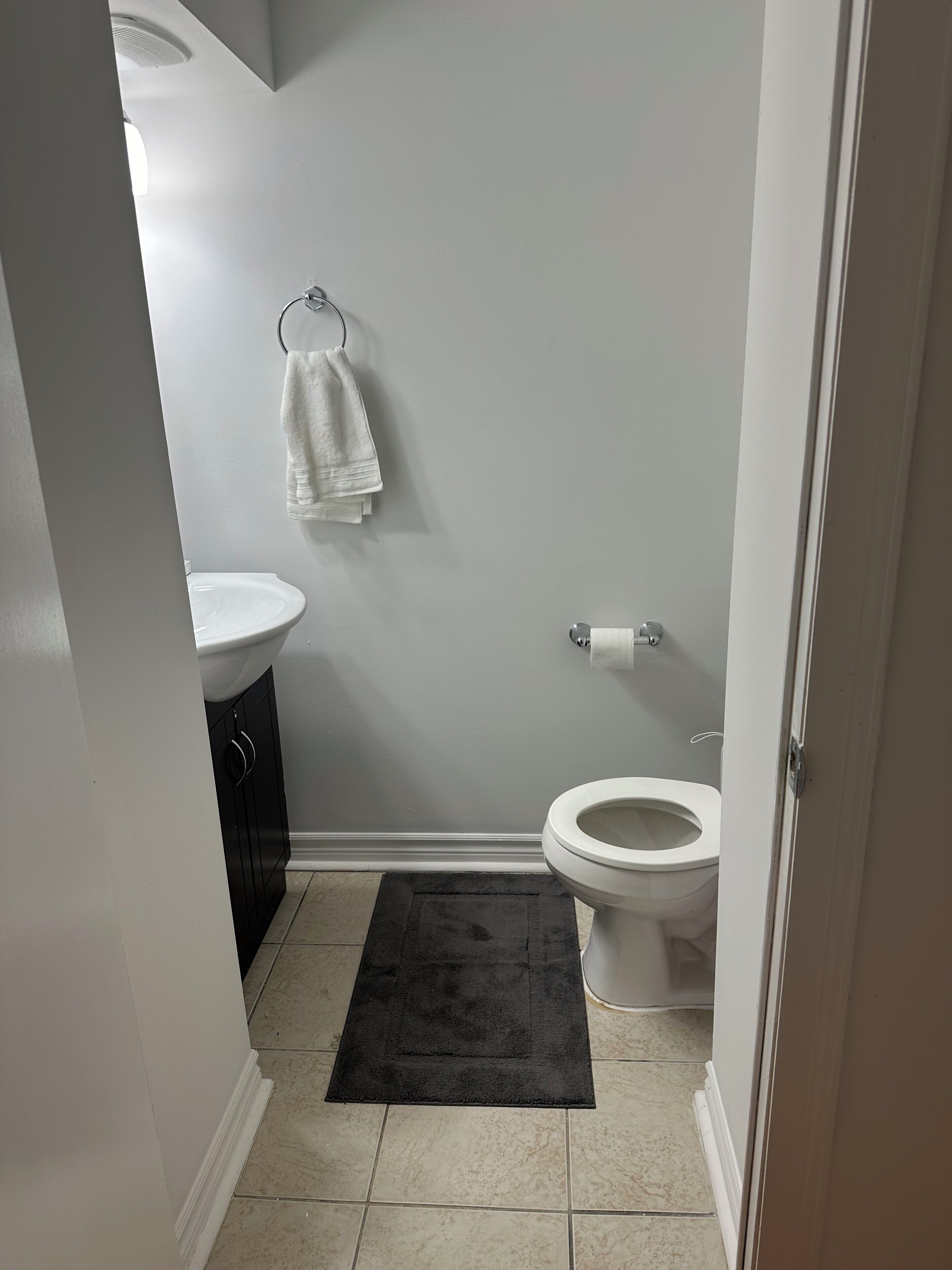 A small bathroom with a toilet, sink, and a towel hanging on the wall.