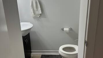 A small bathroom with a toilet, sink, and a towel hanging on the wall.