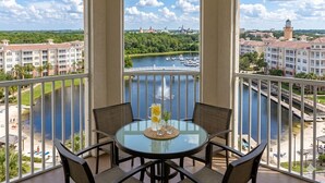 Een balkon met een glazen tafel, stoelen en een pitcher limonade.