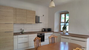 Una cucina moderna con mobili in legno, un tavolo da pranzo, sedie, un forno a microonde e una finestra con una pianta.