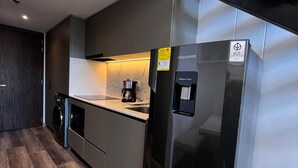 Una cocina moderna con un refrigerador de acero inoxidable, un horno empotrado y una cafetera.