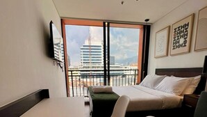 Una habitación de hotel moderna con balcón, una cama, un escritorio y dos sillas.