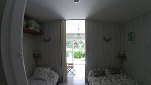 A small, single-room hotel with two beds, a window, and a door leading to a balcony. - Sea, Relaxation and Pink Granite / 3-person apartment 300m from the beach (Trébeurden)