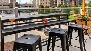 A balcony with outdoor seating, a clear view of buildings, and a street in the background.