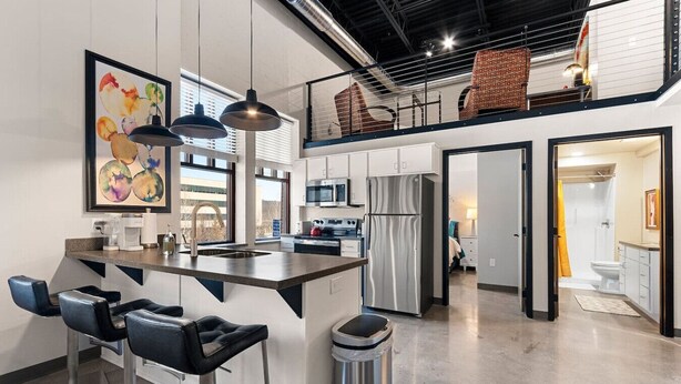 A modern kitchen with a central island, bar stools, and pendant lighting.