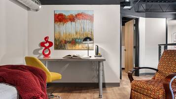 A modern office space with a desk, a yellow chair, a red abstract sculpture, and a patterned armchair.