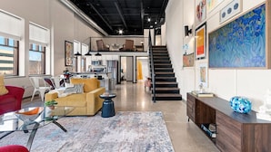 A spacious living area with a staircase, modern furniture, and artwork on the walls.