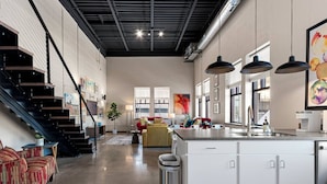 A spacious interior with a kitchen island, staircase, and seating area.