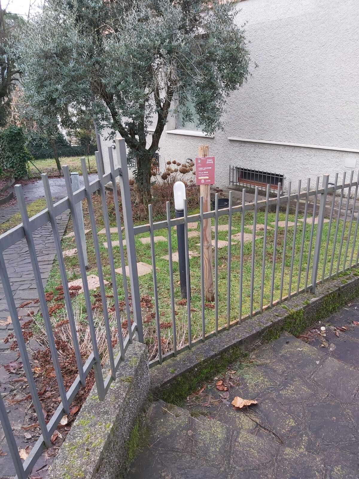 A gated area with a metal fence, a signpost, and a building with a stone wall.