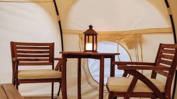 A tent interior with a table, two chairs, and a lantern.