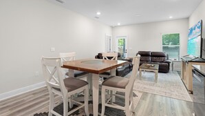 Un salon moderne comprenant une table à manger, des chaises, un canapé et un téléviseur.