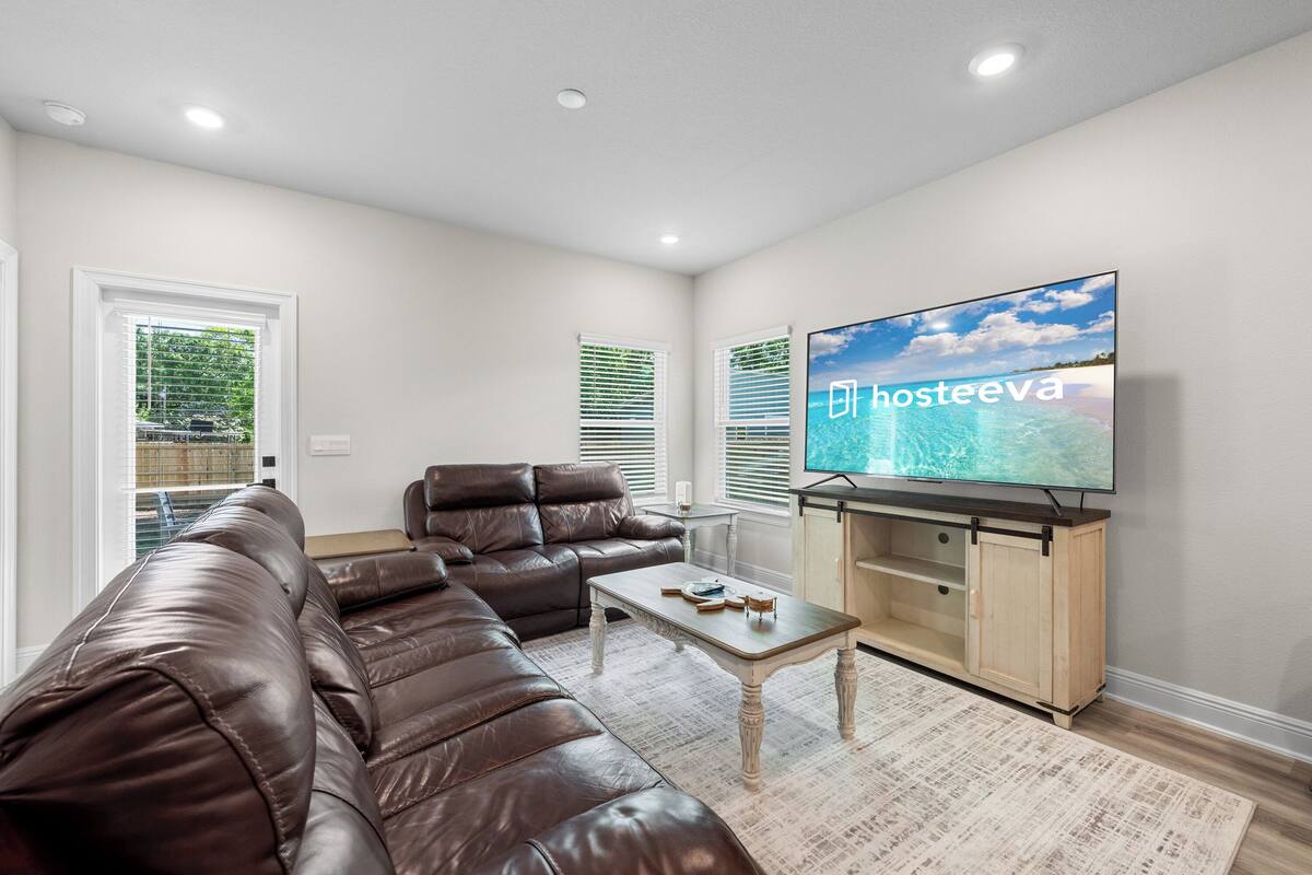 A living room with a brown leather sofa, a coffee table, a flat-screen TV, and a wooden cabinet.