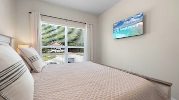 Un dormitorio con cama, televisor montado en la pared y vistas al exterior a través de una ventana.