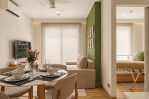 A modern living space with a dining area, a sofa, a bed, and a television. - Luxury 2br in Laguna - Golf view - skypark pool (Choeng Thale)