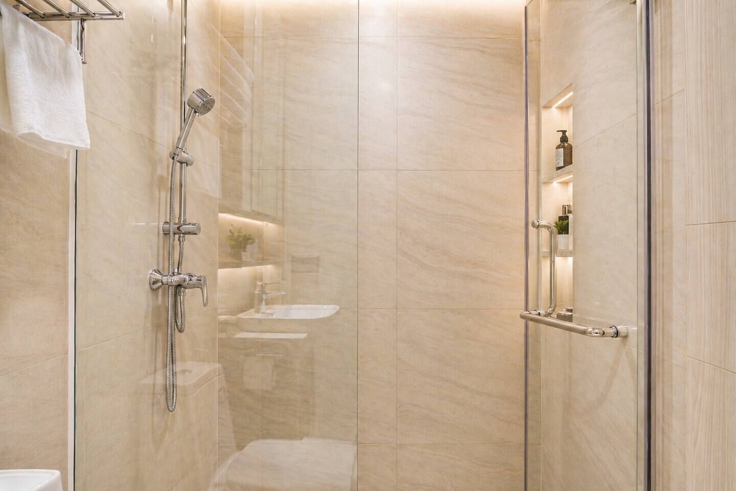 A modern bathroom with a glass-enclosed shower, a visible sink, and a towel rack.
