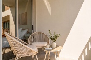 A balcony with wicker chairs, a small table, and a potted plant. - Luxury 2br in Laguna - Golf view - skypark pool (Choeng Thale)