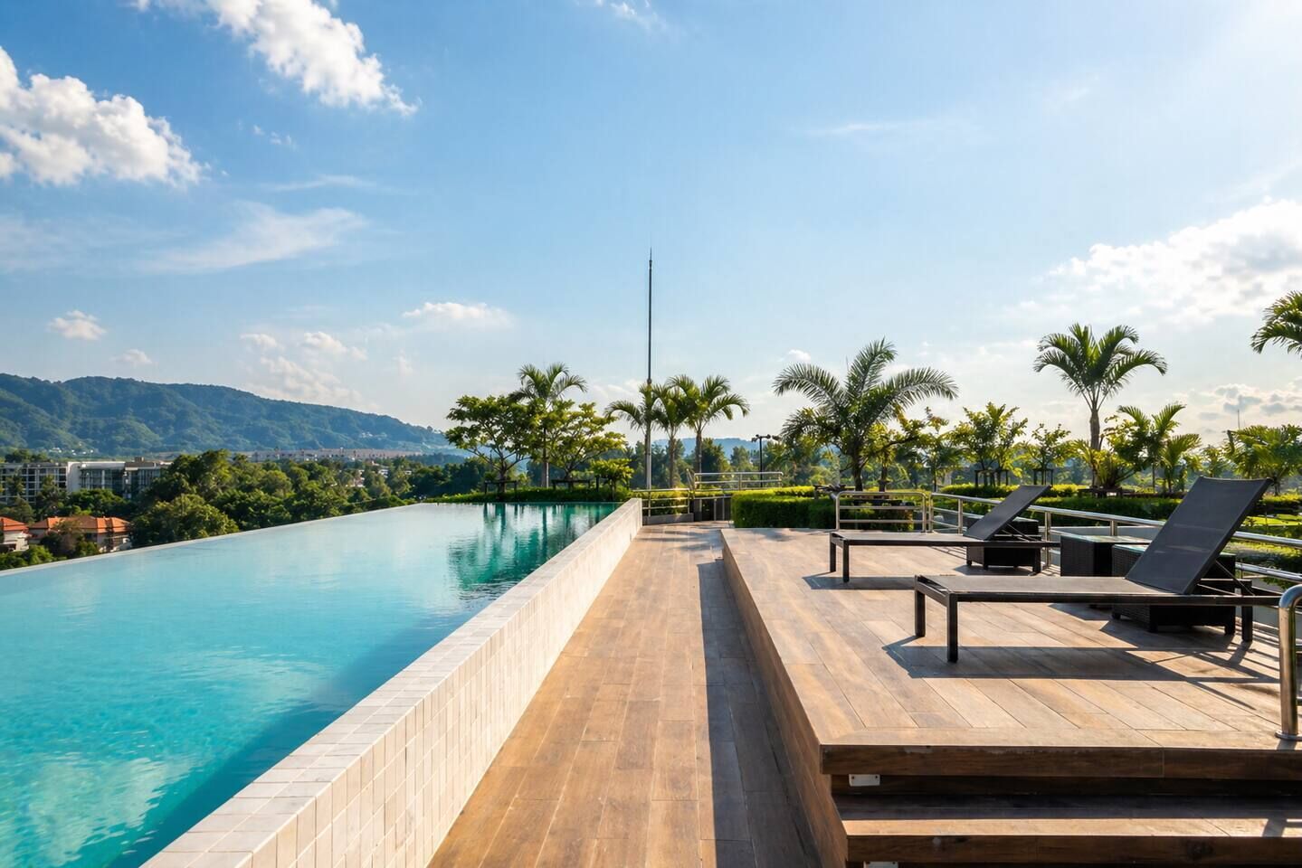 Zona de piscina con vista despejada a la piscina, sillas de descanso y una cadena montañosa distante.