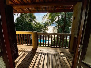 A wooden deck with a view of a swimming pool and palm trees.