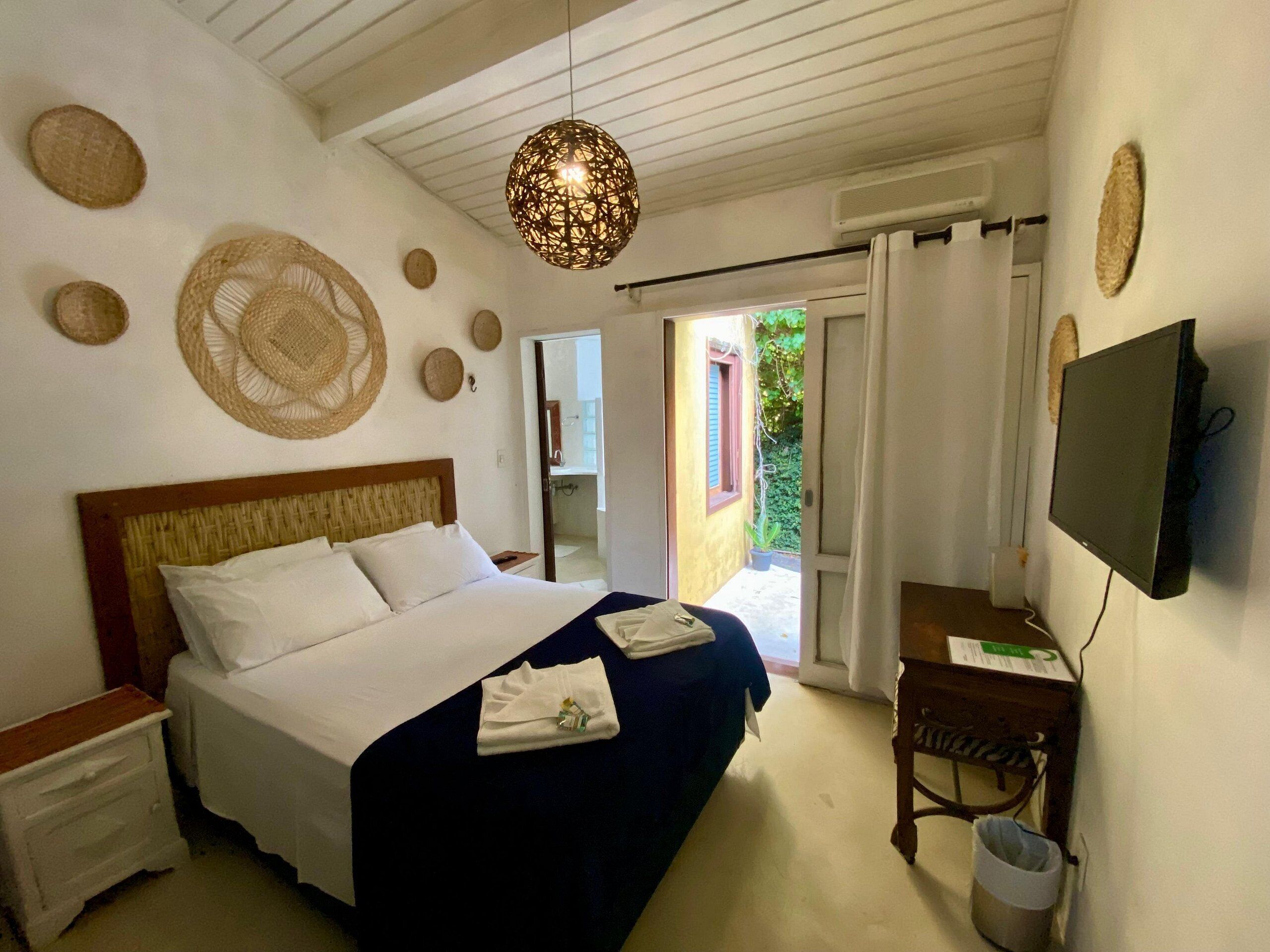 A bedroom with a bed, bedside tables, a TV, and a view of the outside.