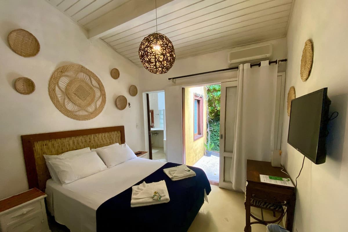 A bedroom with a bed, bedside tables, a TV, and a view of the outside.