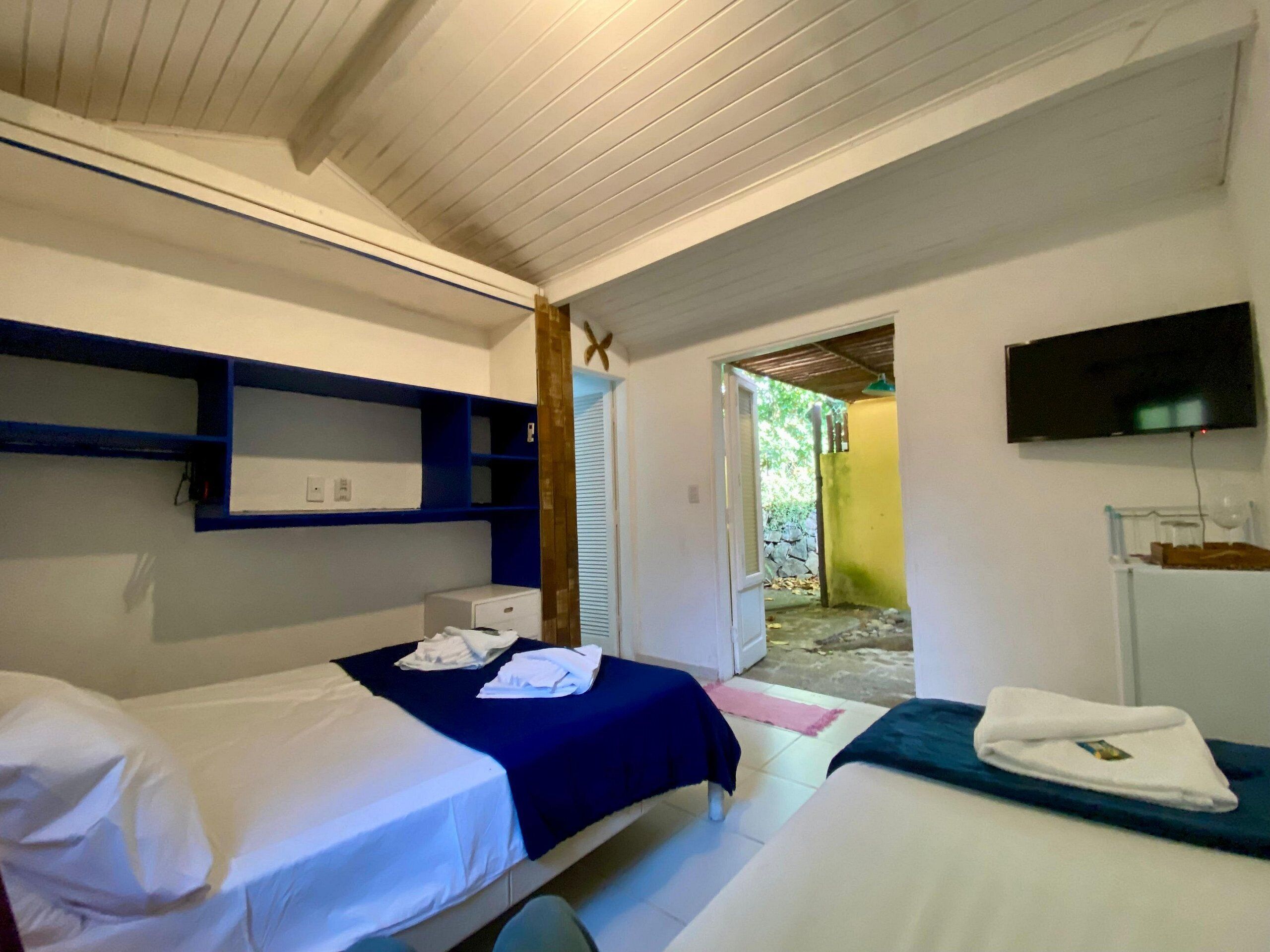 A room with two beds, a television, and a small window.