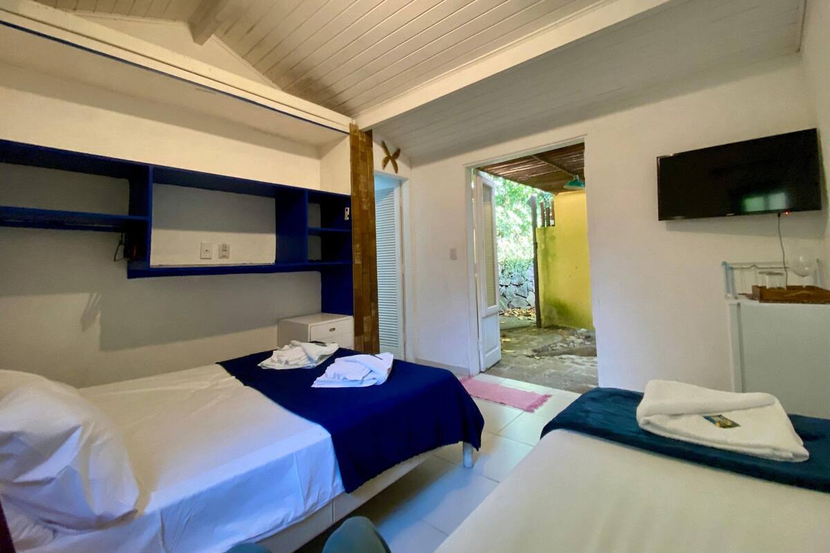 A room with two beds, a television, and a small window.