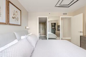 Ein Hotelzimmer mit Bett, Nachttisch, einem gerahmten Bild und einer Tür zu einem Badezimmer.