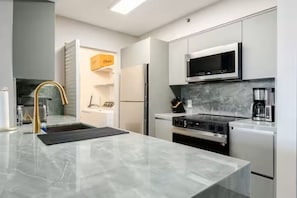 Eine moderne Küche mit einem Edelstahl-Kühlschrank, einem eingebauten Backofen, einer Mikrowelle und einer Kaffeemaschine.