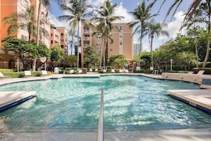 Ein Swimmingpool, umgeben von Palmen und Hotelgebäuden.