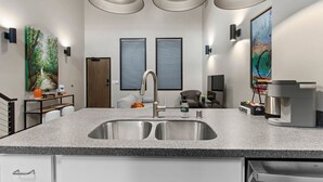 A modern kitchen with a double sink, pendant lighting, and a coffee machine. - Lambeau Loft - Downtown GB & KI Convention (Green Bay)