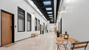 A corridor with a high ceiling, white walls, and a wooden bench. - Lambeau Loft - Downtown GB & KI Convention (Green Bay)