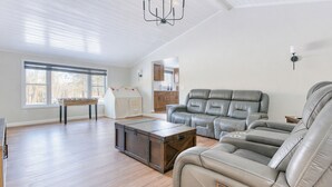 A spacious living room with a leather sofa, a wooden coffee table, and a chandelier. - Catskills getaway with all modern comforts (Kerhonkson)