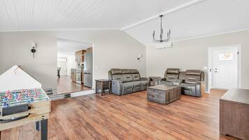 A spacious living room with a foosball table, leather recliners, and a wooden coffee table.