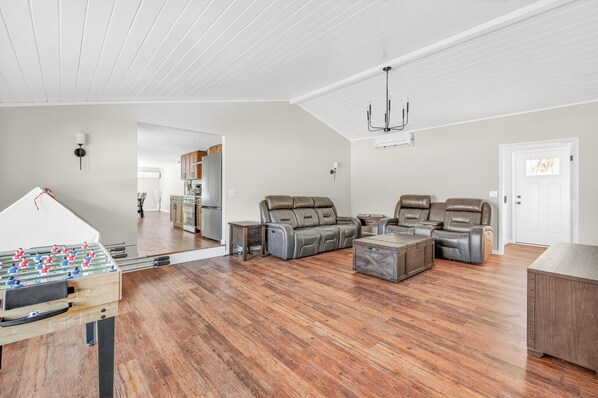 A spacious living room with a foosball table, leather recliners, and a wooden coffee table.