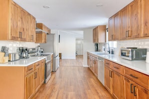 A modern kitchen with wooden cabinets, stainless steel appliances, and a white countertop.