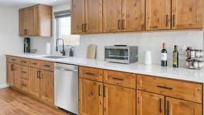 A kitchen with wooden cabinets, a dishwasher, a toaster, and various kitchen appliances. - Catskills getaway with all modern comforts (Kerhonkson)