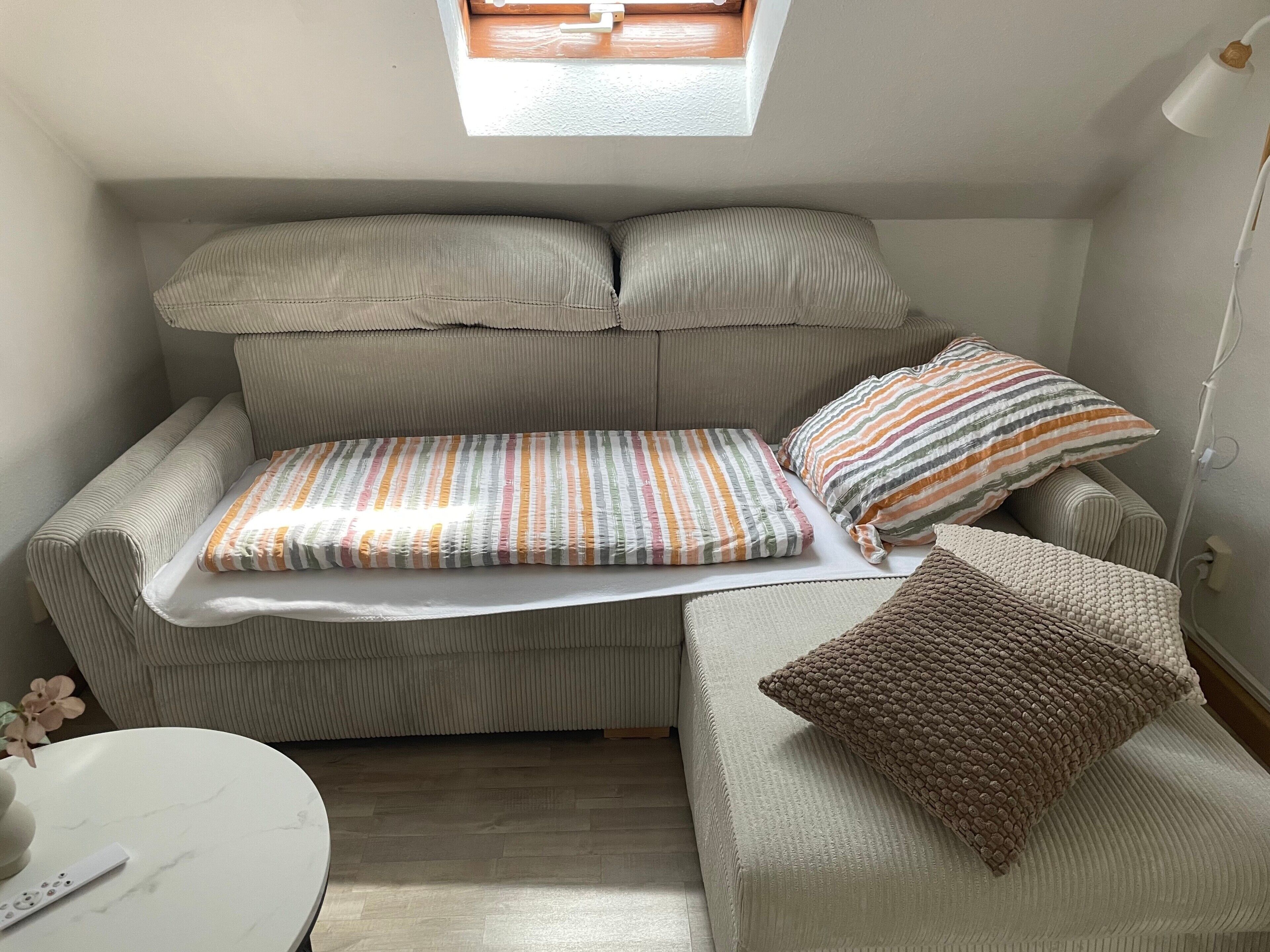 Ein gemütlicher Wohnbereich mit Sofa, kleinem Tisch und Fenster.