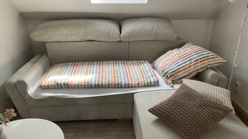 Ein gemütlicher Wohnbereich mit Sofa, kleinem Tisch und Fenster.