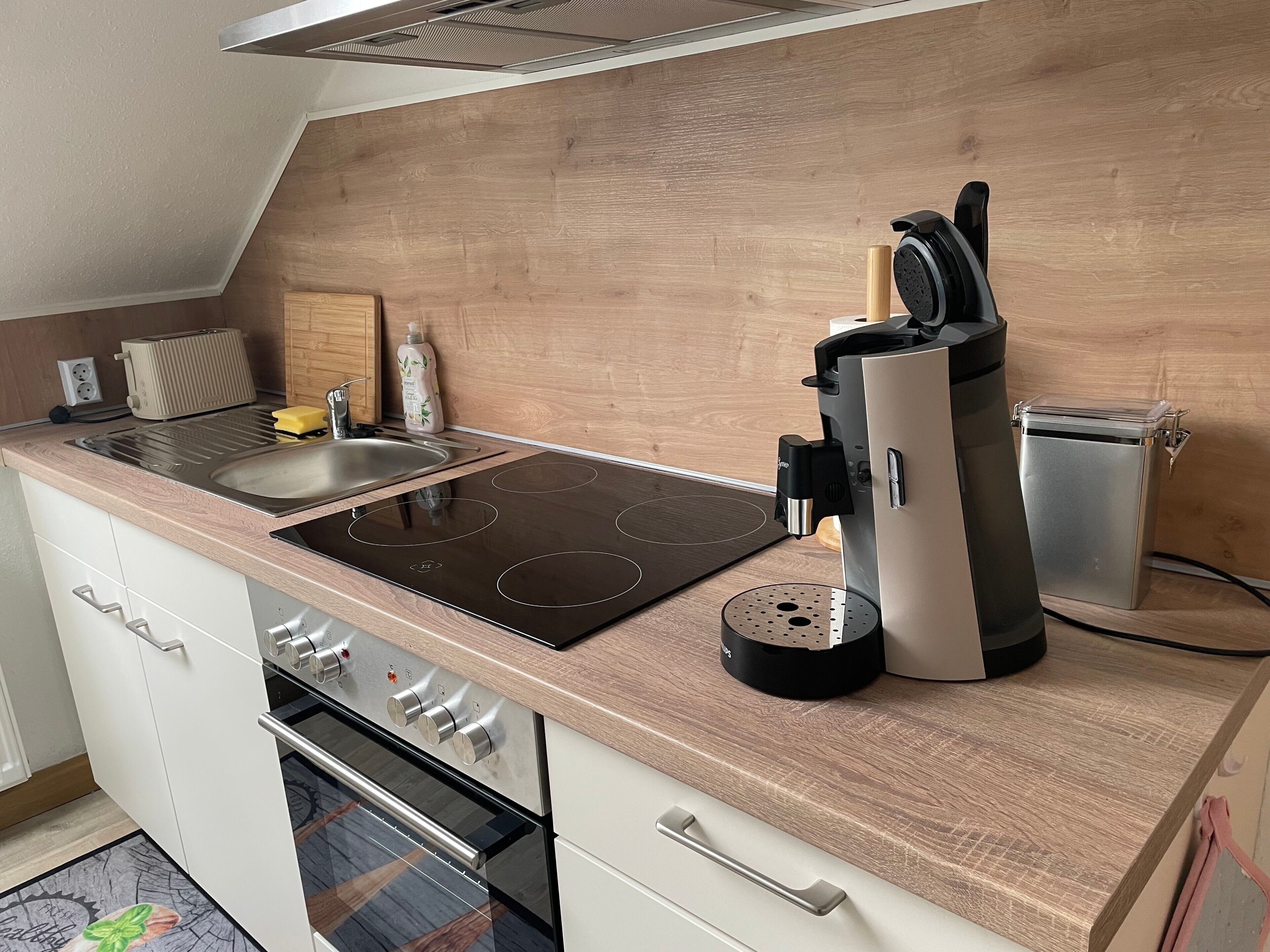 A modern kitchen with a built-in oven, a stovetop, a coffee maker, and a toaster.