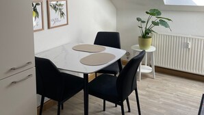 Uma cozinha moderna com armários brancos, uma mesa de jantar com cadeiras pretas e um claraboia acima.