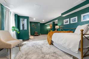 A bedroom with a bed, a chair, a desk, and artwork on the walls. - AfterWIRTZ - Walking distance to Lambeau/Resch Ctr (Green Bay)