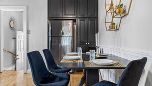 Eine moderne Küche mit dunklen Schränken, einem Edelstahl-Kühlschrank und einem Esstisch für vier Personen.