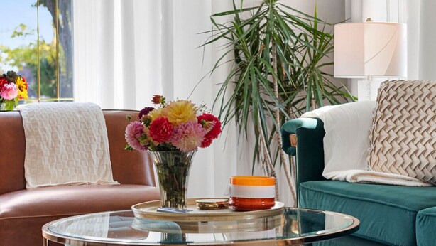 Ein Wohnzimmer mit einer Couch, einem Couchtisch, einer Vase mit Blumen und einer Lampe.