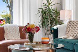 A living room with a sofa, a coffee table, a vase with flowers, and a lamp. - AfterWIRTZ - Walking distance to Lambeau/Resch Ctr (Green Bay)
