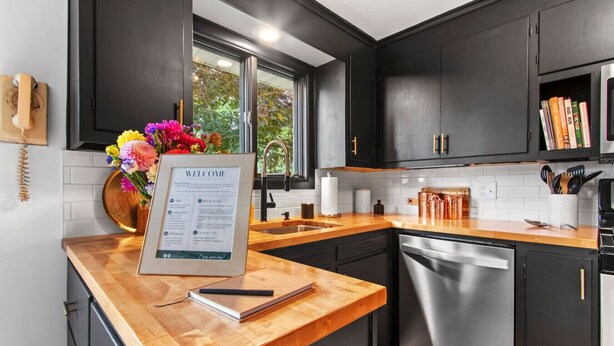 A modern kitchen with dark cabinets, a wooden countertop, a sink, and a dishwasher. - Biemeret Garden - Steps from Lambeau, Resch Center (Green Bay)