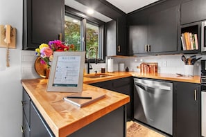 Een moderne keuken met donkere kastjes, een houten aanrecht, een spoelbak en een vaatwasser.