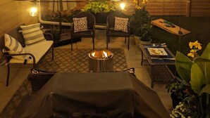 A patio with a fire pit, outdoor seating, string lights, and potted plants. - Biemeret Garden - Steps from Lambeau, Resch Center (Green Bay)
