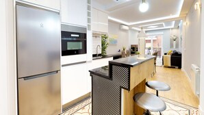 Een moderne keuken met roestvrijstalen apparatuur, een centraal kookeiland en een eetgedeelte met barkrukken.