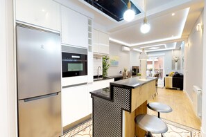 A modern kitchen with stainless steel appliances, a central island, and a dining area with bar stools. - Charming Modern Apartment in Central Madrid (Madrid)