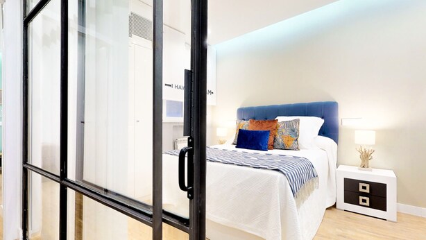 Een moderne slaapkamer met een bed, nachtkastje en een glazen scheiding.